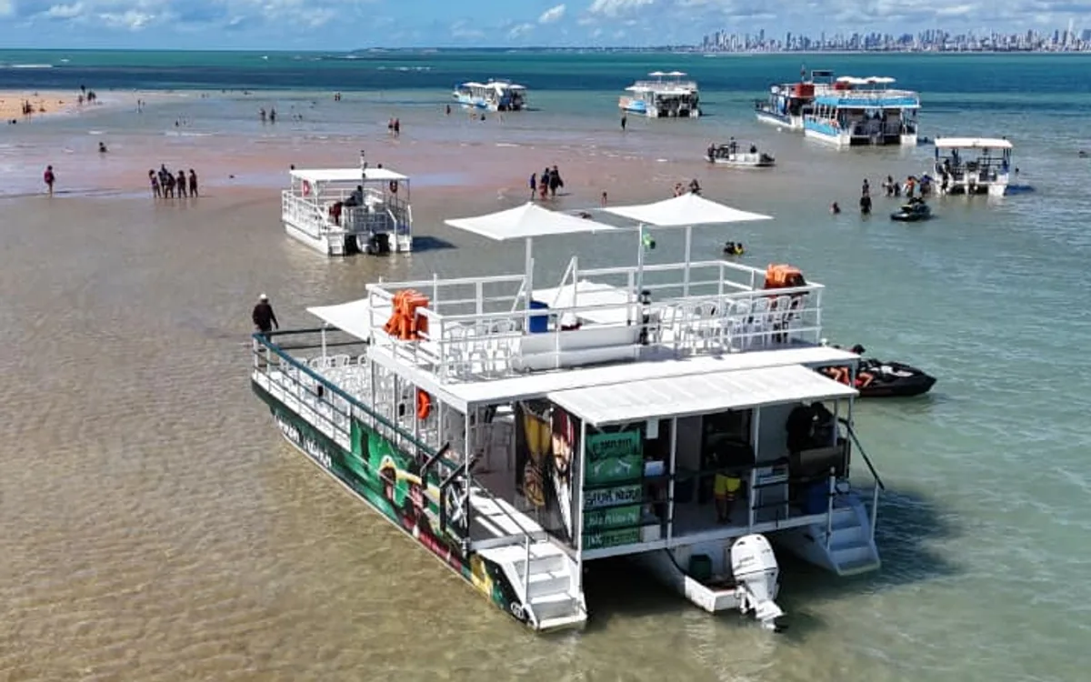 Catamarã ancorado em Areia Vermelha com banco de areia e João Pessoa ao fundo